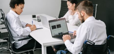 Drei Personen sitzen an einem Tisch und Arbeiten